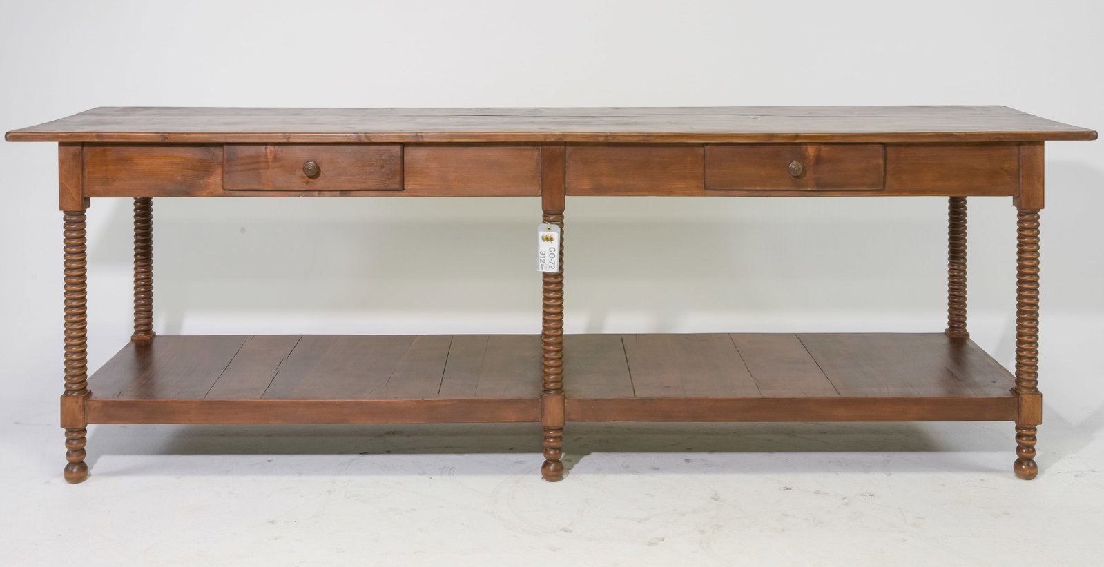 French Pine Draper's Table with Bobbin Legs: French pine draper's table featuring a long rectangular plank top above a central drawer with turned wood pull. Six finely bobbin-turned supports frame a spacious full-length lower shelf, with turned 