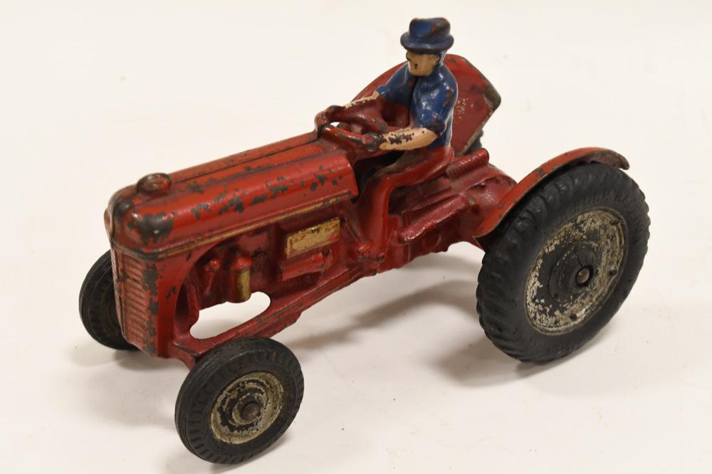 Arcade Ford 9N Tractor: Nice Arcade Ford 9N cast iron tractor circa 1939. Painted in red with gold accents, seated driver with blue hat and shirt with red pants, black rubber tires with painted enters. Hard piece to find. Di