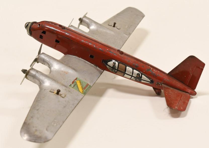 Louis Marx Tin Bomber Plane: Nice Marx tin bomber plane with 2 bombs. Displays nicely with the original Louis Marx decal. Has some paint loss. Wingspan measures approximately 14 1/2" long.