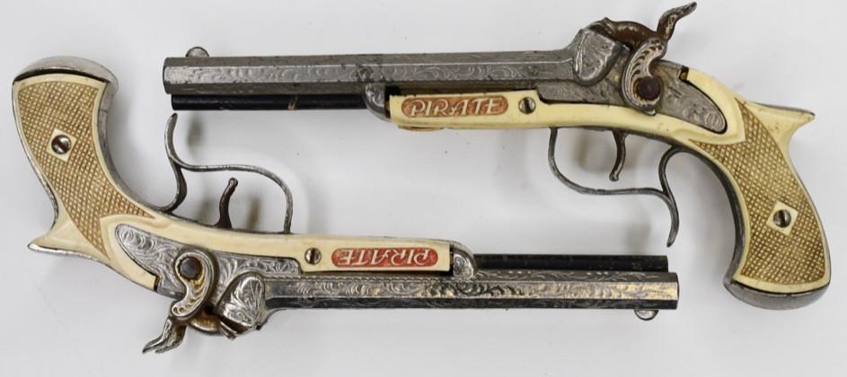 (2) Hubley Flintlock Double-Barrel Pirate Cap Guns: Lot of 2 Hubley flintlock double-barrel Pirate cap gun pistols. Both display nicely with some corrosion and wear from play and age. Each measures approximately 9 1/2" across.