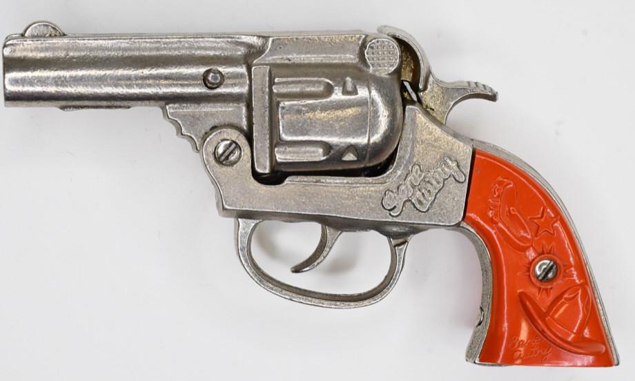 Kenton Gene Autry Repeating Cap Gun Pistol: Kenton Gene Autry cap gun pistol with red grips. The one grip has a crack in it. Displays nicely with wear from play and age. The trigger works. Measures approximately 6 1/4" long.
