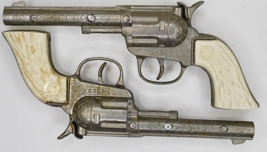 Set of Hubley Rodeo Cap Gun Pistols: Set of Hubley Rodeo cap gun pistols with white grips. Both are complete and the triggers work. Display nicely with wear from use and age. Measures approximately 7 1/2" long.