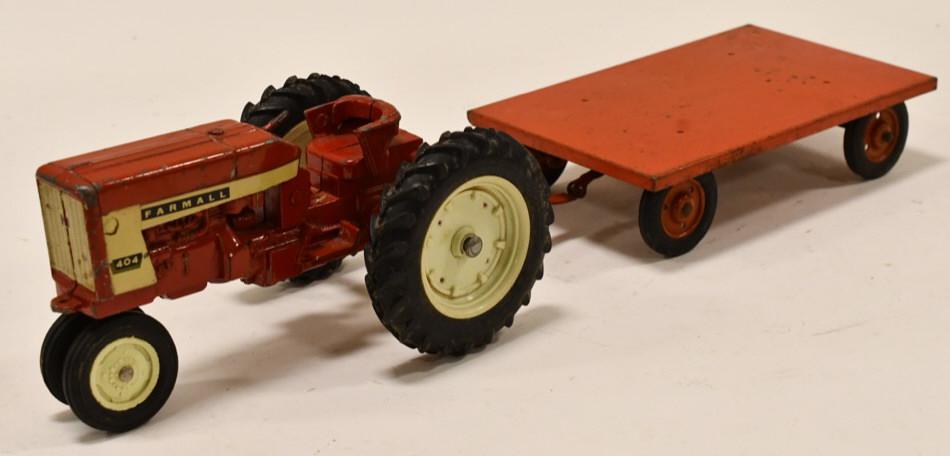 1/16 Ertl Farmall 404 Narrow Front w/ Trailer: 1/16th scale Ertl Farmall 404 narrow front tractor with flatbed trailer. Has paint loss and wear from play and age. The Farmall 404 is missing the steering wheel. Displays nicely.
