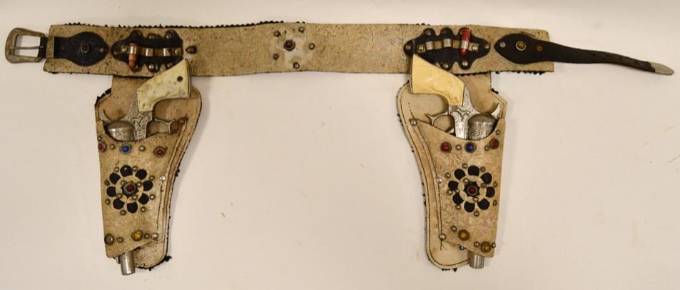 Leslie-Henry Wild Bill Hickock Cap Gun Set: Leslie-Henry Wild Bill Hickock cap gun set with tooled leather holster. The holster has wear to leather. The guns have wear to the grips, but display nicely considering age. Gun measures approximately