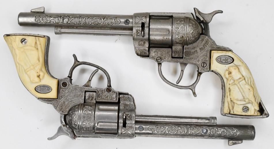 Leslie-Henry Gene Autry 44 Cap Gun Set: Leslie-Henry Gene Autry 44 cap gun set. The one has a cracked grip. Both have wear from play and age. Both of the triggers work. Gun measures approximately 10 1/2" long.