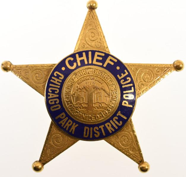Obsolete Chicago Park District Police Chief Badge: Nice obsolete ornate gold tone five-point star Chicago Park District Police Chief badge. Badge is in nice condition with light wear from use and age. Has pinback. Back is marked "C.H. Hanson". It meas