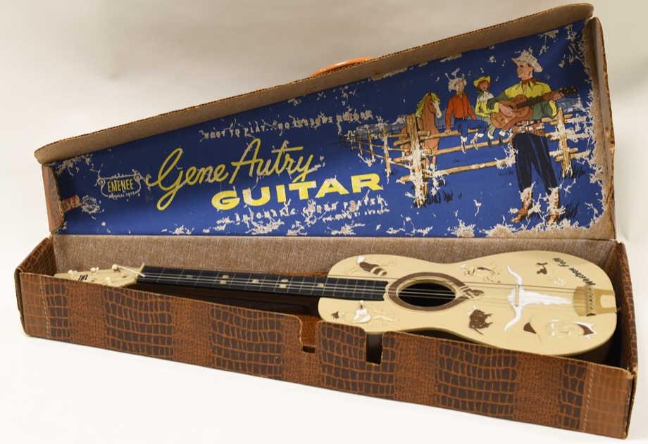 Emenee Gene Autry Western Folk Guitar No. 601: Nice Emenee Gene Autry Western Folk guitar no. 601 with the box. Box has some wear from storage and display. The guitar is missing one string. Overall measures approximately 31" long.