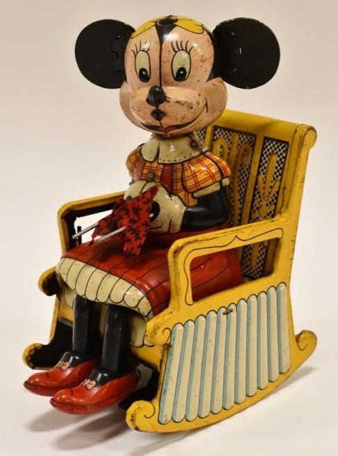 Linemar Tin Kitting Minnie Mouse in Rocking Chair: Linemar tin litho windup knitting Minnie Mouse in rocking chair. Displays nicely with some light paint loss and wear from play and age. The windup mechanism works. Measures approximately 7" tall.