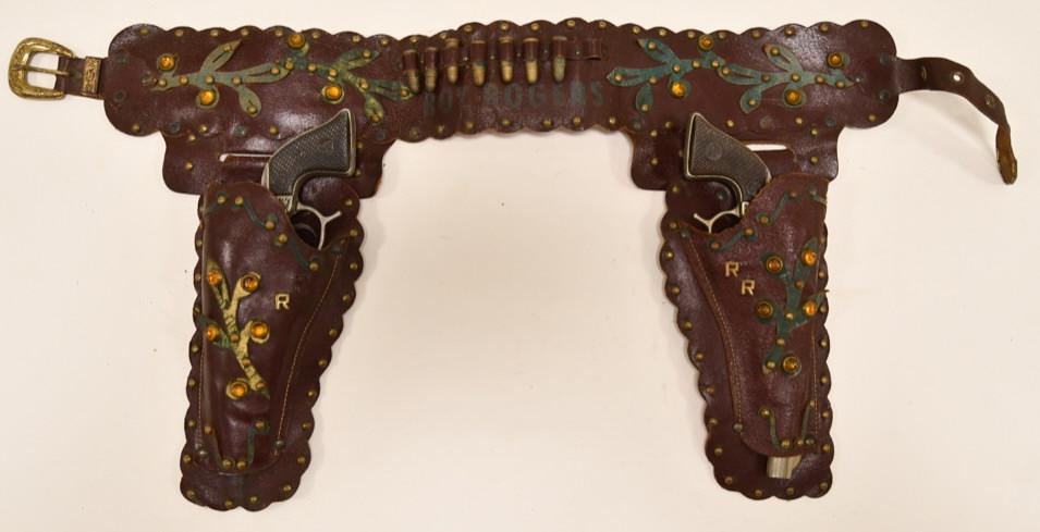 Geo. Schmidt Roy Rogers Cap Gun Set with Holster: Geo. Schimdt Roy Rogers cap gun set with fancy, jeweled, leather holster. The cap guns display nicely with wear from age and play. Both of the triggers do not work. They display well with a Roy Rogers