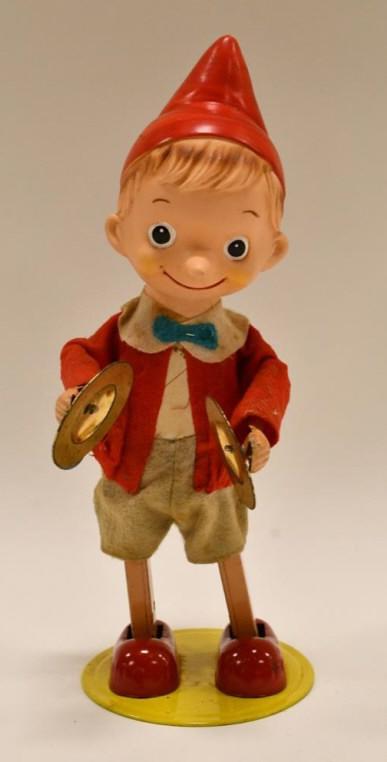 Japan Tin Windup Pinocchio Playing Cymbals: Japan tin windup Pinocchio playing the cymbals. The windup works, but sometimes needs some assistance. Pinocchio's face is made of plastic, with cloth clothes, and a tin body. Displays nicely with wea