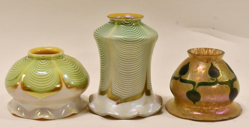 (3) Quezal & Loetz Art Glass Lamp Shades: Lot of three unsigned Quezal & Loetz Art Glass lamp shades. Two have a pulled feather design with gold aurene linings and one has a leaf design. Great condition with no chips or cracks.The tall feathe