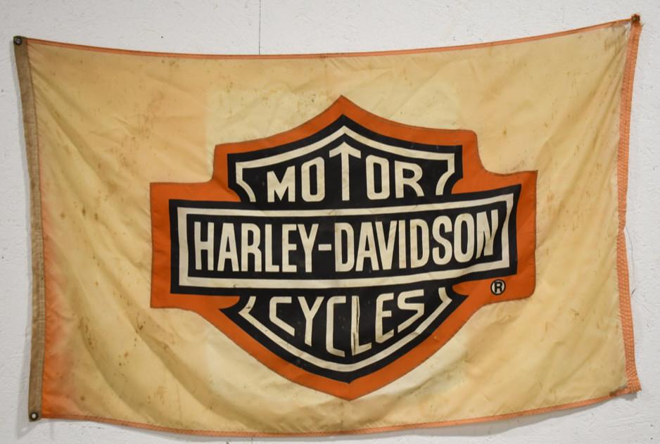 Vintage Harley-Davidson Advertising Flag: Vintage Harley-Davidson advertising fabric flag. Flag is in worn condition with fading, discoloration, rips, and wear from use and age. Still displays well. Measures approximately 57" across by 36" ta