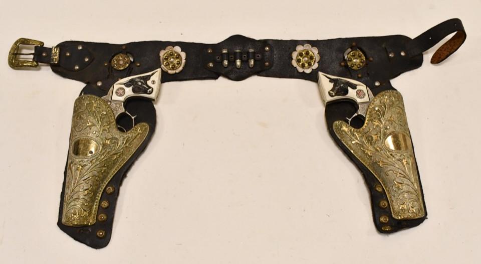 Hubley Texan Jr. Cap Gun Set w/ Holster: Hubley Texan Jr. cap gun set with leather holster. The triggers work. The guns have some corrosion and wear from use and age. The holster has metal scabbards. Displays nicely with wear from use and ag