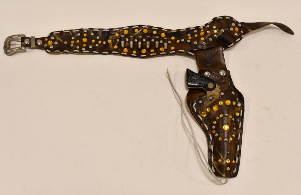 Gold Hopalong Cassidy Cap Gun w/ Camo Holster: Gold Wyandotte Toys Hopalong Cassidy cap gun with camoflauge holster. The cap gun has some discoloration, tarnish, and corrosion from use and age. The trigger works. Displays nicely. Gun measures appr