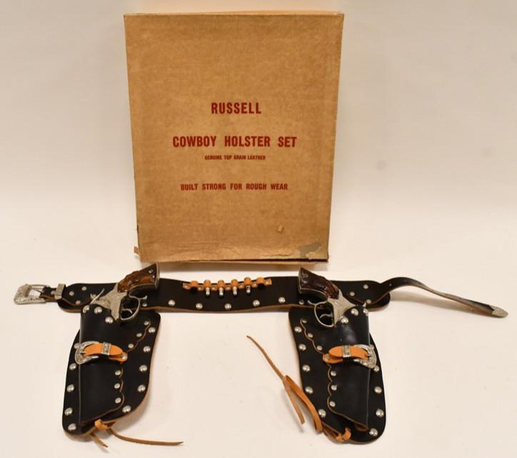 Russel Cowboy Holster Set w LH Smoky Joe Cap Guns: Russel Cowboy holster set with Leslie-Henry Smoky Joe Cap Guns and a double leather holster. The triggers work. The guns have some corrosion and wear from age. The box has wear and missing a flap. Dis