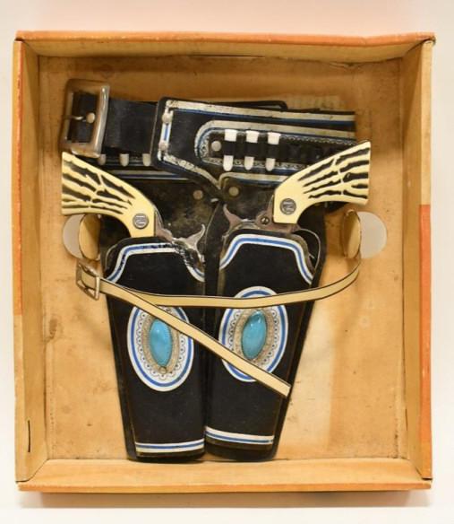 Nichols Leather Cap Gun Holster w Cowhand Cap Guns: Nichols leather cap gun holster with Nichols cowhand cap guns. It comes with the bottom half of the box. The set is dusty and has wear from storage. The triggers work. Displays well. Each gun measures