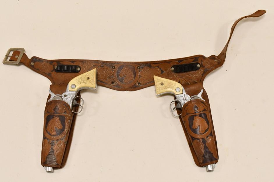 Nichols Stallion 38 Cap Gun Set w/ Leather Holster: Nichols Stallion 38 cap gun set with leather holster. Both triggers work, but the cylinders do not spin when the trigger is pulled. The guns have some corrosion and wear from use and age. The holster 