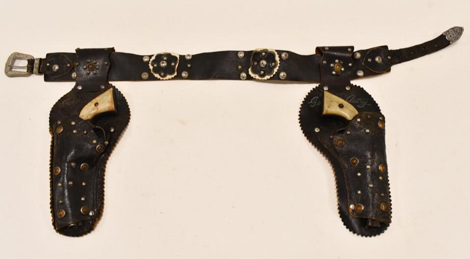 Kenton Gene Autry Cast Iron Cap Gun Set w/ Holster: Kenton Gene Autry cast iron cap gun set with leather holster. The leather holster has wear and tear from use and age. One of the cap guns does not work. The cap guns have corrosion and wear from use a