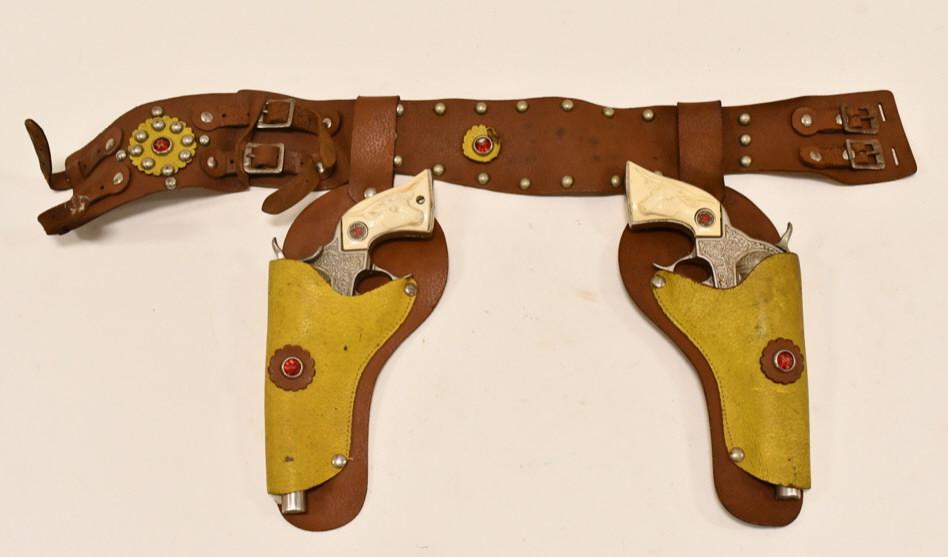 Hubley Texan Cap Gun Set w/ Leather Holster: Hubley Texan cap gun set with leather holster. The cap guns have some corrosion and wear from use and age. The triggers work, but the cylinders do not revolve. The grips have some cracks / repair. The