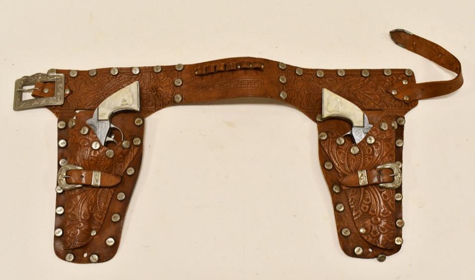 Kilgore Roy Rogers Dale Evans Cap Guns + Holster: Kilgore Roy Rogers cap gun set with leather holster. The cap guns have some corrosion and wear from use and age. Displays well with Roy Rogers trigger grips. The triggers work. The leather holster dis