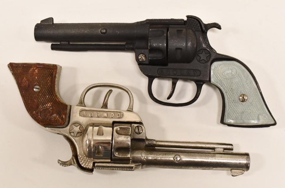 (2) Hubley Cowboy Cap Gun Pistols: Lot of (2) Hubley Cowboy cap gun pistols. The one gun has loose grips. Both have some corrosion and wear from use and age. The triggers work. Display nicely. Each gun measures approximately 8" long.