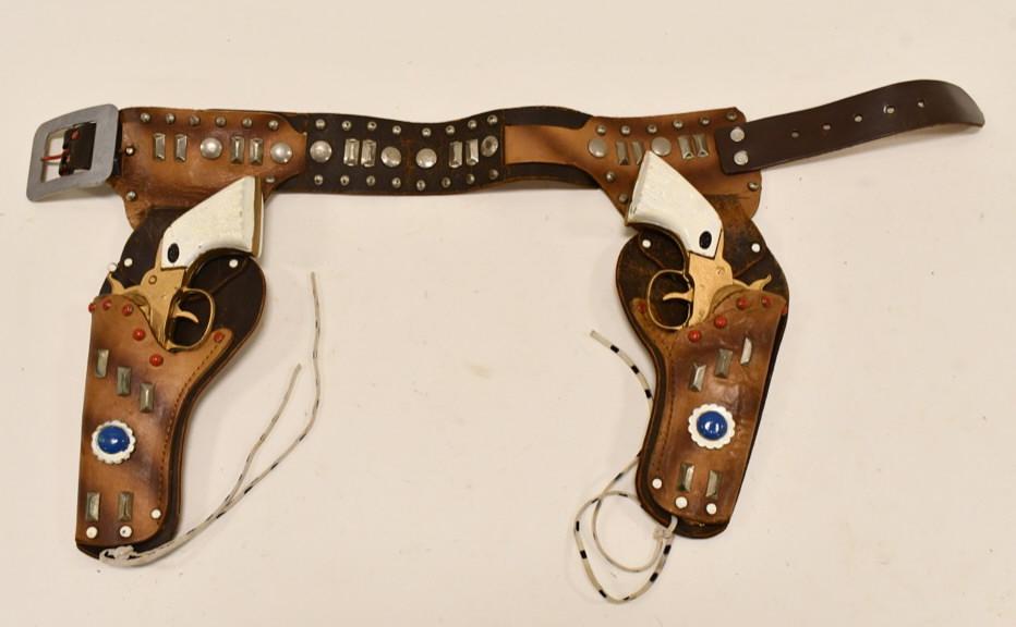 Gold Daisy Cap Gun Set w/ Leather Holster: Gold Daisy cap gun set with leather holster. The guns appear to have been custom painted at some time. The triggers work. The holster has some cracking to the leather and wear from age. Each gun measu