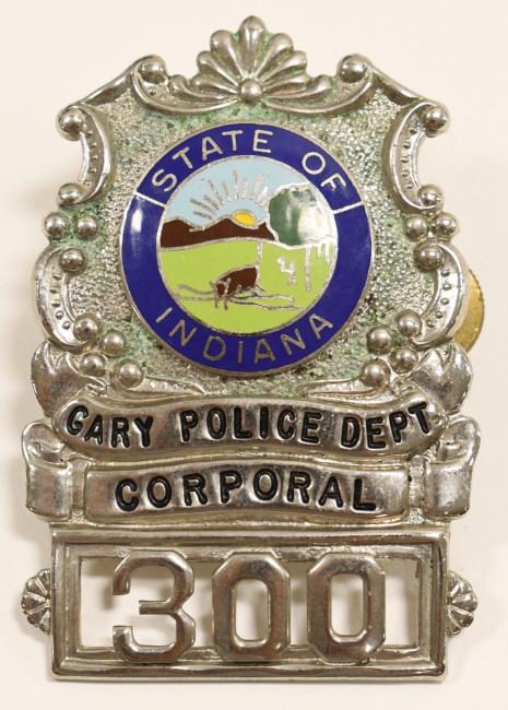 Obsolete Gary IN Police Officer Cap Badge No. 300: Vintage obsolete Gary Indiana Police Officer cap badge No.300 with enameled state seal. Overall fair condition with some surface corrosion. Has screw back. Measures approximately 2-1/2" tall by 1-3/4"