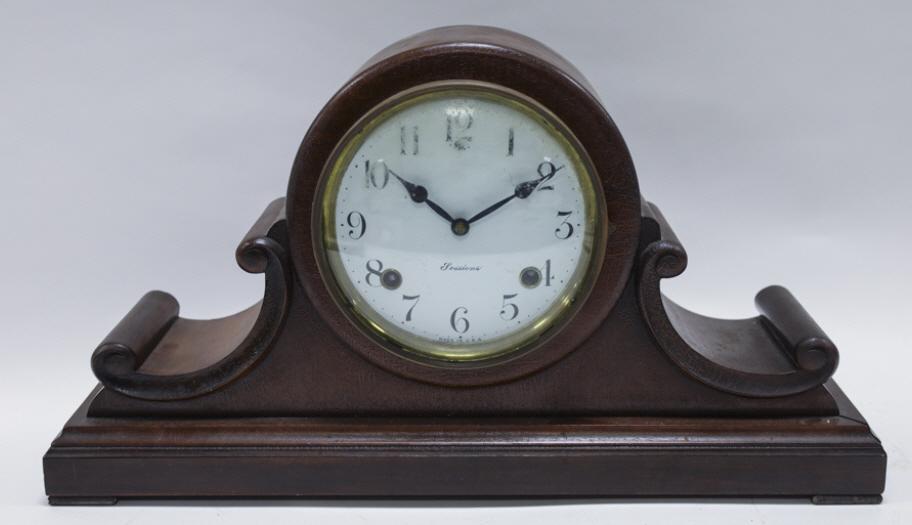 Antique Sessions Wood Mantel Clock: Antique The Sessions Clock Co. wood mantel clock. With pendulum and key. Working condition, has surface wear from age. Made in the USA. Measures 19.25" across, 10.5" tall, 5" deep.