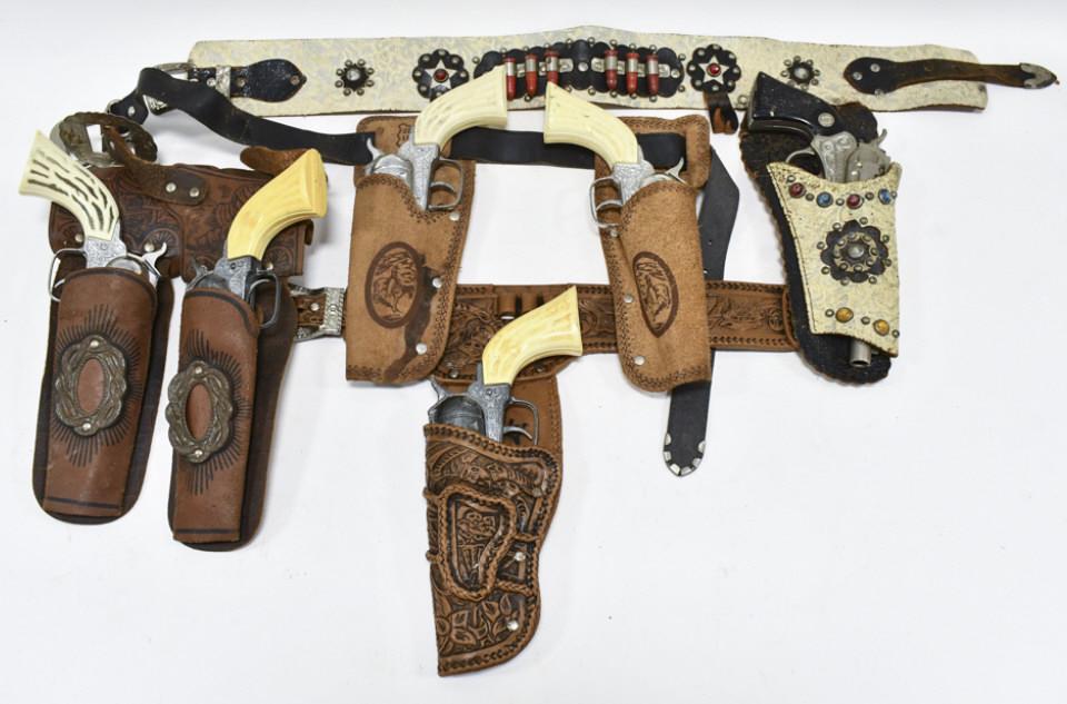 Lot Of Pony Boy Cap Guns w/ Leather Holsters: Lot includes (6) Pony Boy cap guns. The cap guns vary in age and condition. Also includes (2) single holsters, and (2) dual holsters. Largest gun measures approximately 10" long.