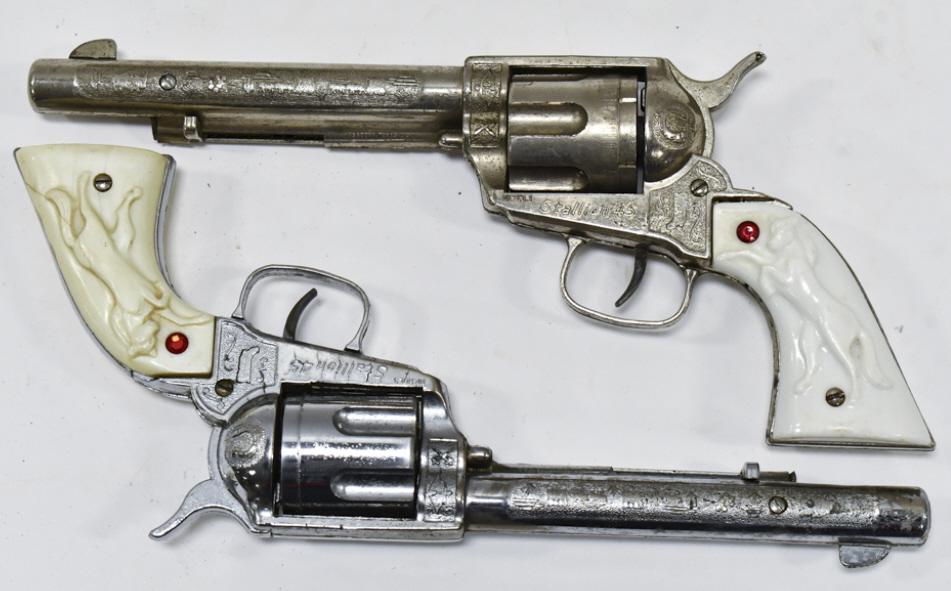 (2) Nichols Stallion 45 Cap Guns: Pair of Nichols Stallion 45 Cap Guns. The one grip has a chip in it. Both have some corrosion and wear from play and age. Each gun measures approximately 11-1/2" long.