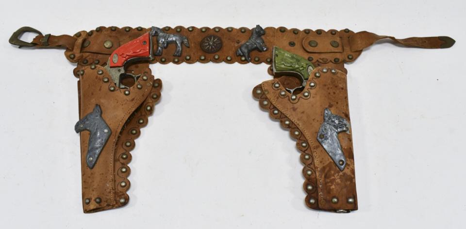Leslie Henry Gene Autry 44 Cap Guns w/ Holster: Leslie Henry Gene Autry 44 cap guns with leather holster. The cap guns have wear from use and age. They have different colored grips. The holster has some cracking and wear. Each gun measrures approxi