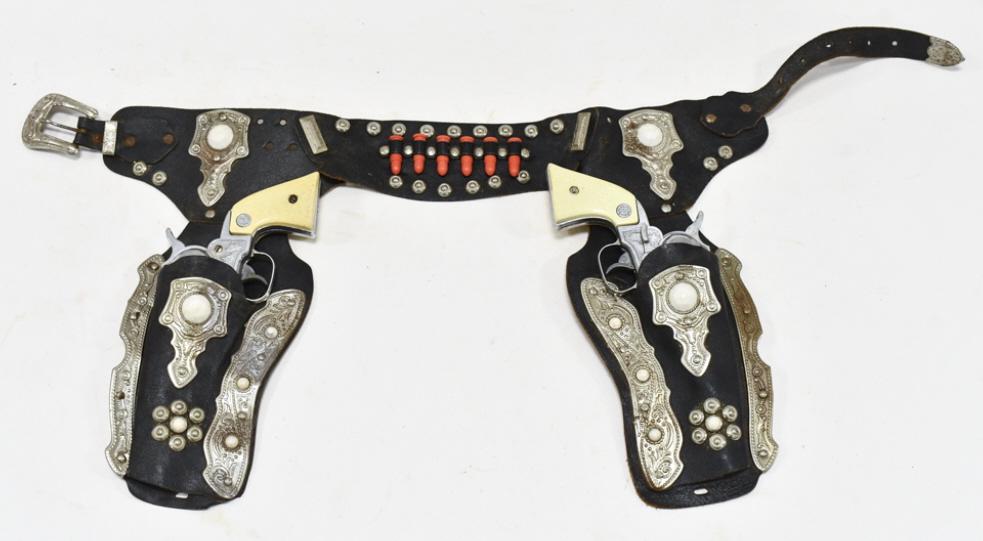 Nichols Stallion 38 Cap Gun Set w/ Leather Holster: Nichols Stallion 38 cap gun set with leather holster. The cap guns have some corrosion and wear from use and age. The holster has some cracking and wear from age. Each gun measures approximately 9" lo