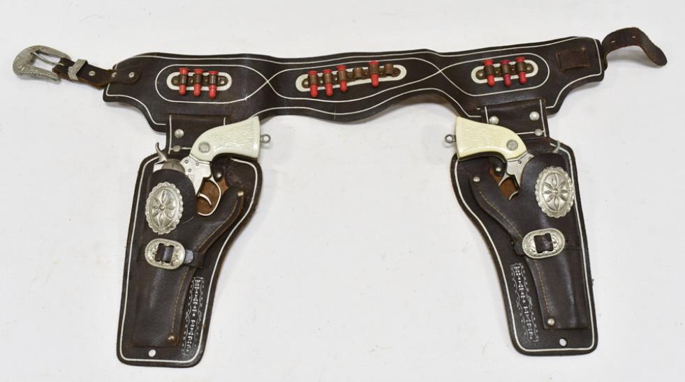 Actoy Wyatt Earp Cap Gun Set w/ Leather Holster: Actoy Wyatt Earp cap gun set with Wyatt Earp leather holster. The cap guns have corrosion and wear from use and age. The holster has some cracking and wear from age. Each gun measures approximately 8-