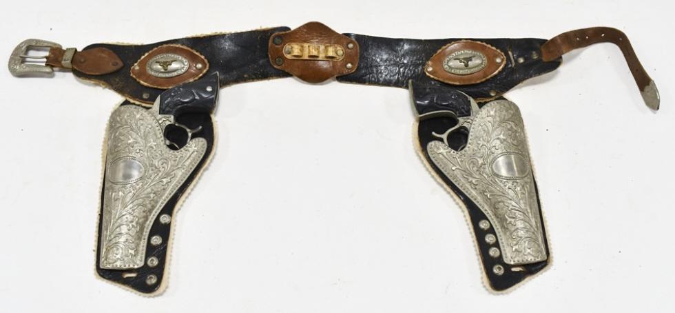 Leslie Henry Champion Cap Gun Set w/ Holster: Leslie Henry Champion / Gene Autry cap gun set with leather holster. The guns have some corrosion and wear from use and age. The holster has some cracking and wear from age. Each gun measures approxim