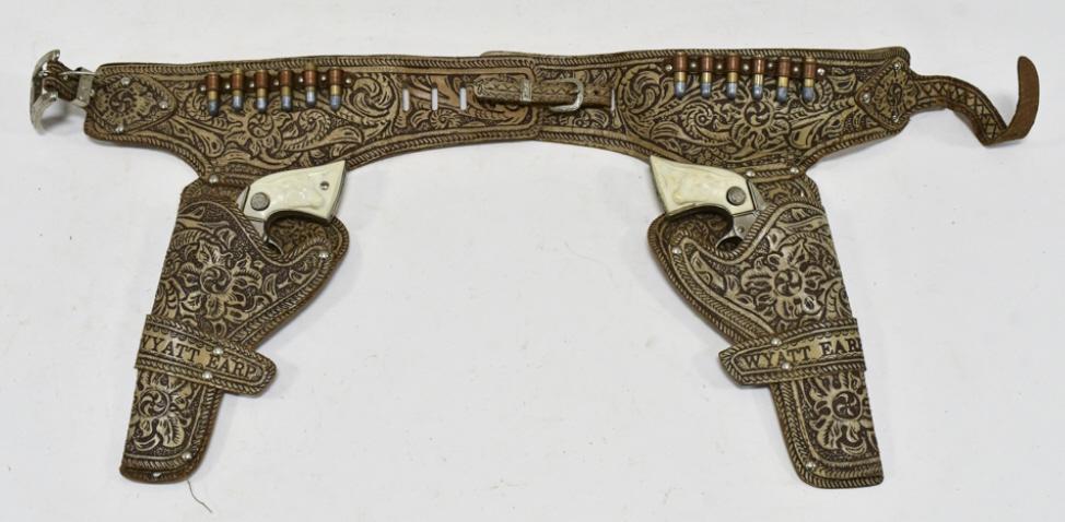 Long Island Wyatt Earp Cap Gun Set w/ Holster: Long Island Die Casting Inc. Wyatt Earp cap gun set with Wyatt Earp leather holster. The guns have corrosion and wear from use and age. The holster has some cracking. Each gun measures approximately 8