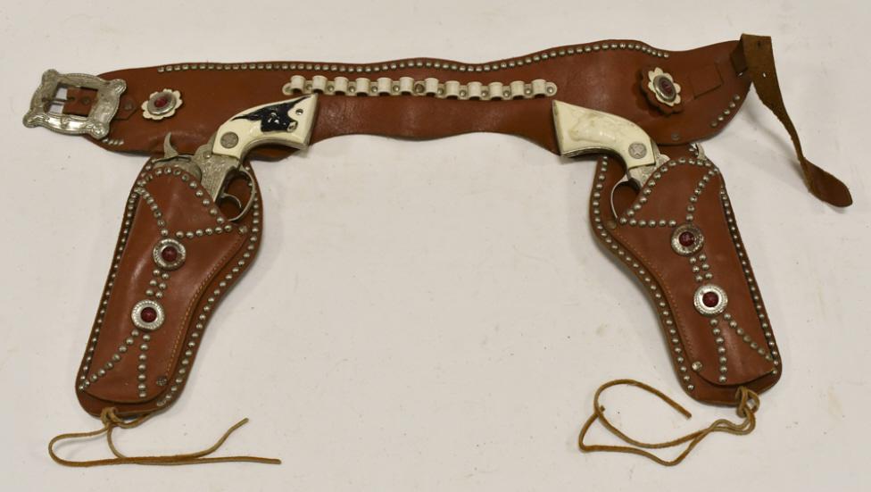 Hubley Texan Jr. Cap Gun Set w/ Leather Holster: Hubley Texan Jr. cap gun set with leather holster. The cap guns have some wear from use and age. The holster has some cracking from age. Each gun measures approximately 8-1/2" long.