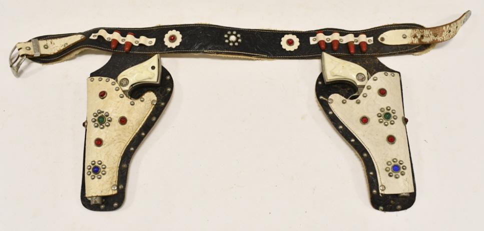 Hubley Texan Jr. Cap Gun Set w/ Holster: Hubley Texan Jr. cap gun set with leather holster. The cap guns have some wear from use and age. The holster has some cracking from age. Each gun measures approximately 9" long.