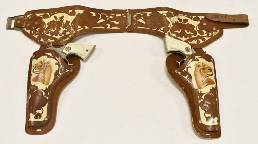 Hubley Texan Jr. Cap Gun Set w/ Leather Holster: Hubley Texan Jr. cap gun set with leather holster. The guns have some corrosion and wear from use and age. The holster has some cracking. Each gun measures approximately 8-1/2" long.