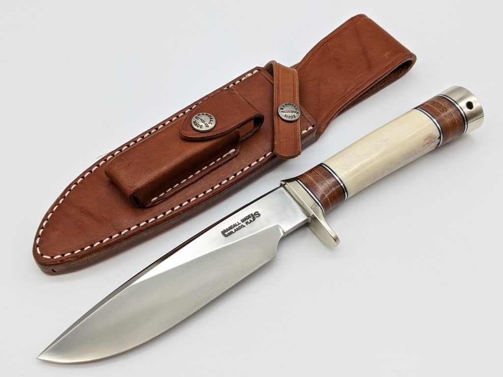 Randall Made Model 25 Trapper w/ Bone Handle: Randall Made Model 25 Trapper w/ Randall Sheath. Knife features stainless steel blade with thumb notches, down turned single nickel hilt, mastadon bone handle with leather and duralumin spacers, and n