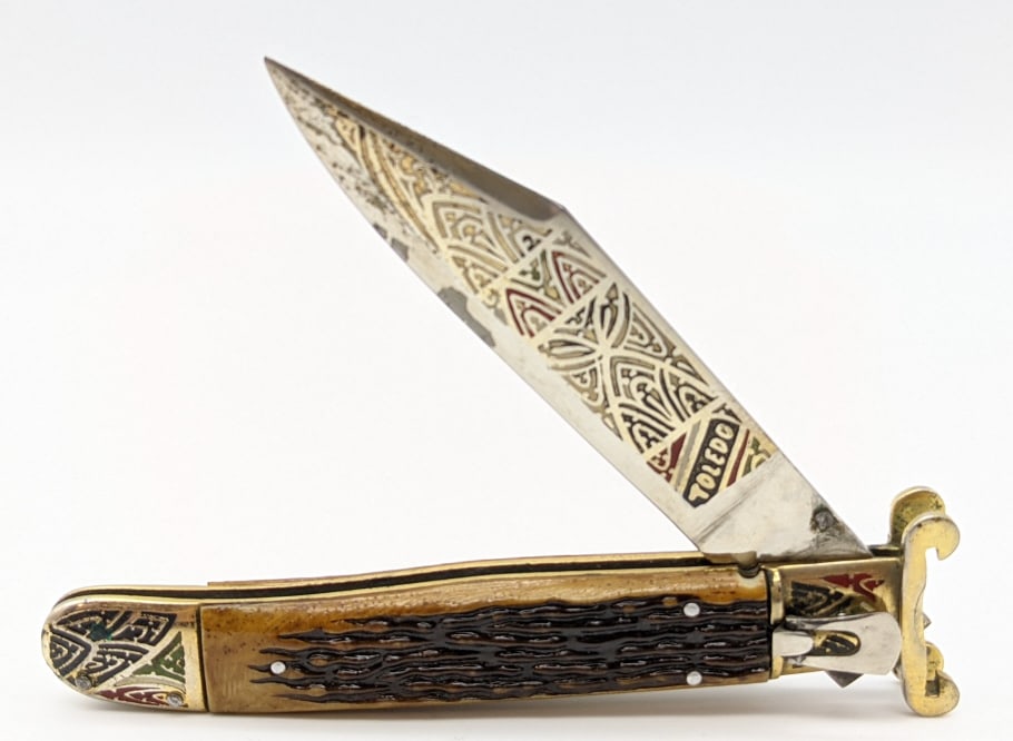 Toledo Decorated Lever Lock Bone Switchblade: Toledo Decorated Lever Lock Bone Switchblade. Knife features decorated etched blade and bolsters and fixed guard. Knife is in good condition with some wear from age. Blade lengths of 4-1/4in and overa