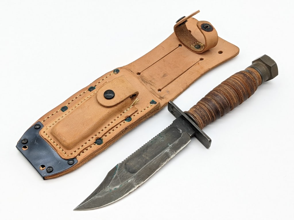 Vietnam USAF Camillus Pilots Survival Knife: Vietnam USAF Camillus 11-1968 Pilots Survival Knife w/ Ontario Sheath. Knife features blackened steel blade with saw tooth spine, square double guard, stacked leather handle, and nut pommel. Knife is