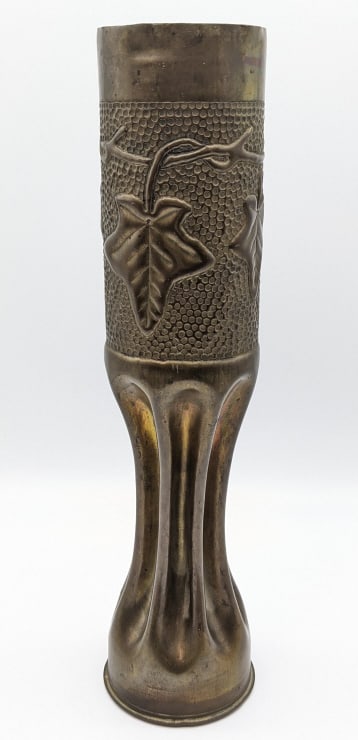 Vtg 75mm Artillery Shell Trench Art: Vtg 75mm Artillery Shell Trench Art. Shell features a leaf vine pattern around the top edge with a dimpled background and ribbed base. Shell is in nice aged condition and displays nicely. Measures 13-