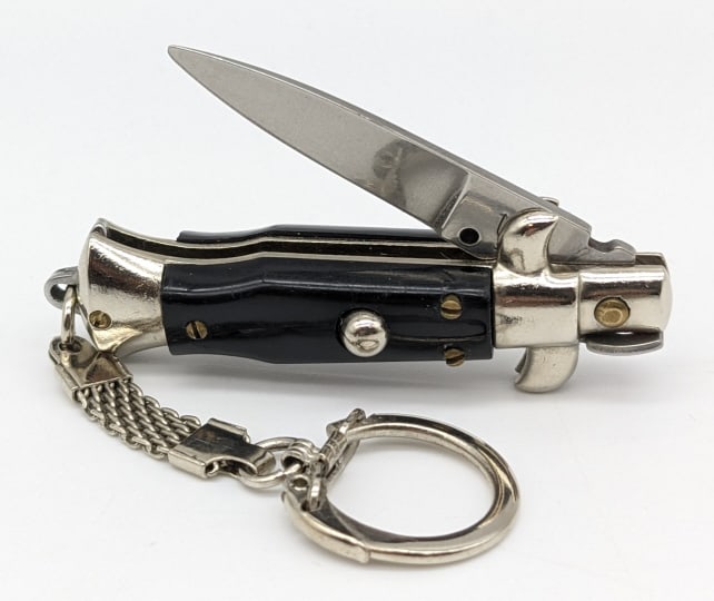 Mini Inox Italy Keychain Stiletto Switchblade: Mini Inox Italy Keychain Stiletto Switchblade Knife. Knife is in very nice condition with a single edge blade, black plastic handle scales, and pick lock locking design. Blade spring is strong, but lo