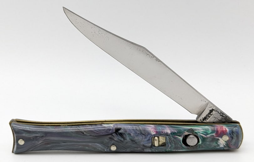 Edgemaster Marbled Fishtail Switchblade: Edgemaster Marbled Fishtail Switchblade. Knife is in nice aged condition with a polished blade and blue marbled plastic handle scales. Blade spring functions but is pretty weak and has a little play w