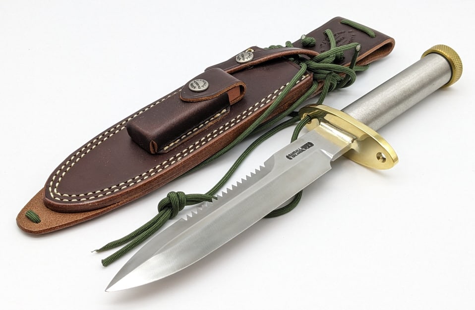 Randall Model 18 Attack Survival Knife w/ Sheath: Randall Model 18 Attack Survival Knife w/ Randall Sheath. Features a sawtooth blade, brass oblong hilt with wrist thong holes, tubular steel handle, and screw off brass butt cap. Knife is in near new 