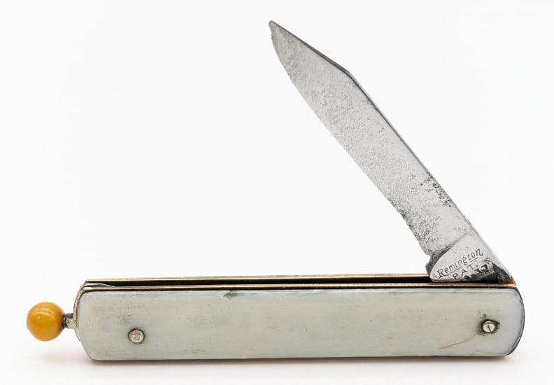 Vtg Remington R-17 Pull Release Switchblade Knife: Vtg Remington R-17 Pull Release Switchblade Knife. Knife is in nice used condition with a red pull ball release, worn blade with material loss and pitting, and white plastic handle scales. Blade sprin