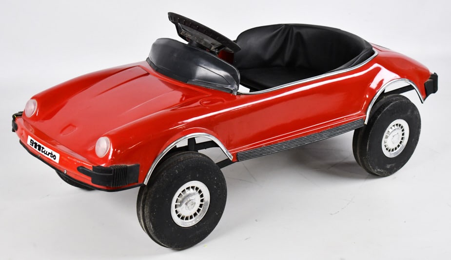 Mini Motors Porsche 911 Turbo Pedal Car: Mini Motors Porsche 911 Turbo pedal car. The car is missing the horn, has decal wear, crack in the steering wheel, and chips from use and handling. Measures approximately 38" long.