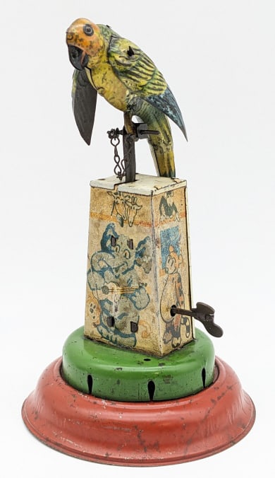 JDN German Tin Windup Parrot: JDN Garman tin windup parrot on stand with animal graphics. Displays well with good color. The windup mechanism works, but the bellows doesn't squeak. The toy has paint chipping and age wear. Measures