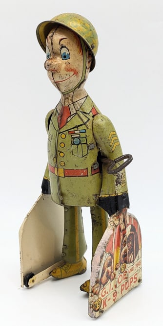Unique Art Tin Litho Wind Up GI Joe and K-9 Pups: Unique Art tin litho windup GI Joe and the K-9 Pups. The toy has some surface rust, discoloration, paint loss, and wear from play / age. The windup mechanism works. Measures approximately 9" tall.