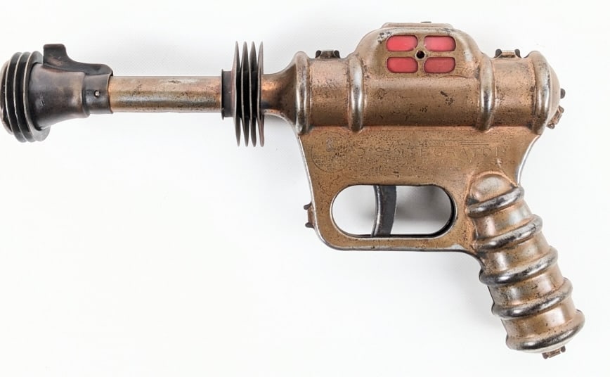 Daisy MFG. Co. Buck Rogers Disintegrator Pistol: Daisy MFG. Co. Buck Rogers Disintegrator ray gun pistol. When the trigger is pulled the gun makes a popping noise. Displays nicely with a copper finish. The gun has scratches, tarnishing, and wear fro